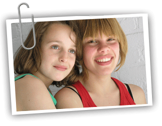 Two twin girls facing the camera and smiling